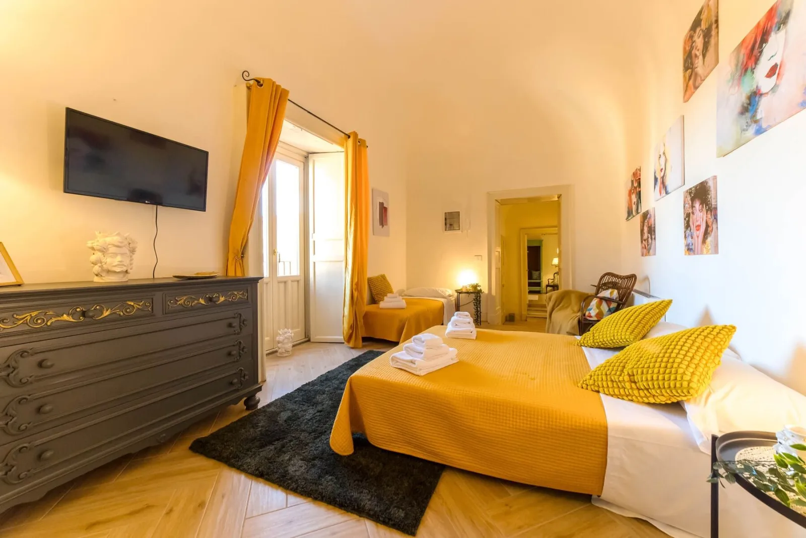 Open bedroom and living area with dresser, TV and yellow throw