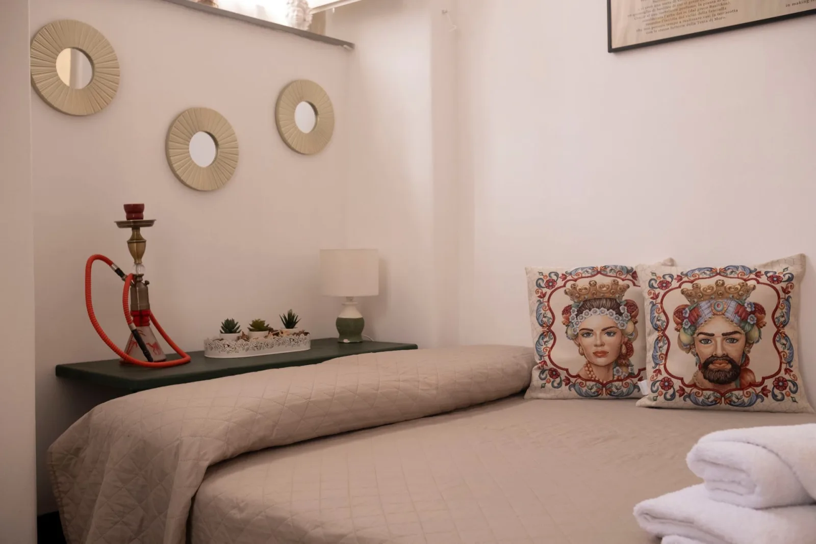Bed with Sicilian-motif cushions and round mirrors