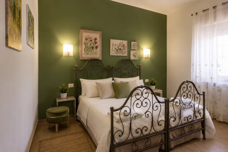 Bedroom with wrought-iron bed and green feature wall