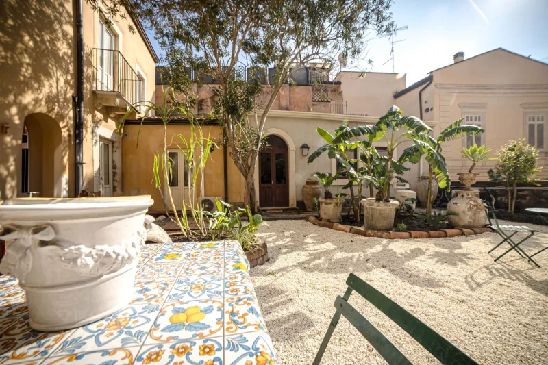 Private courtyard garden with tiled table, plants and palazzo facades