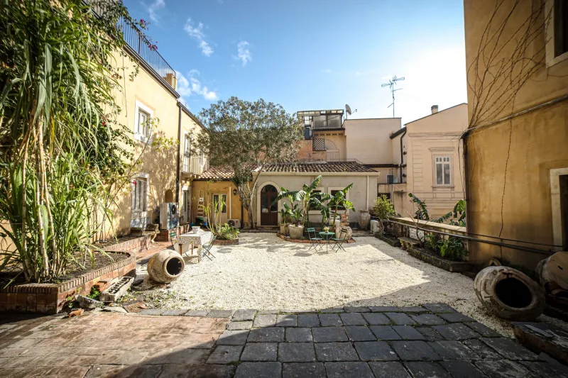 Gravel courtyard with banana plants and terracotta urns