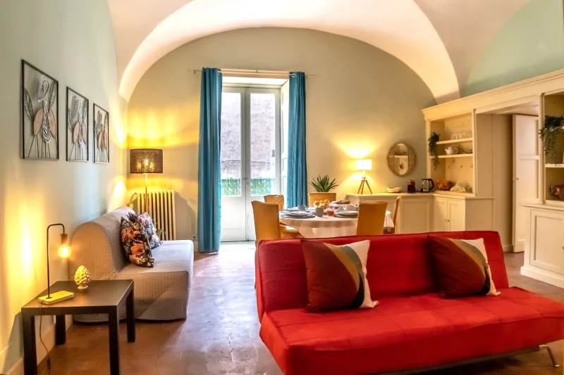 Vaulted living room with red sofa, dining table and balcony doors