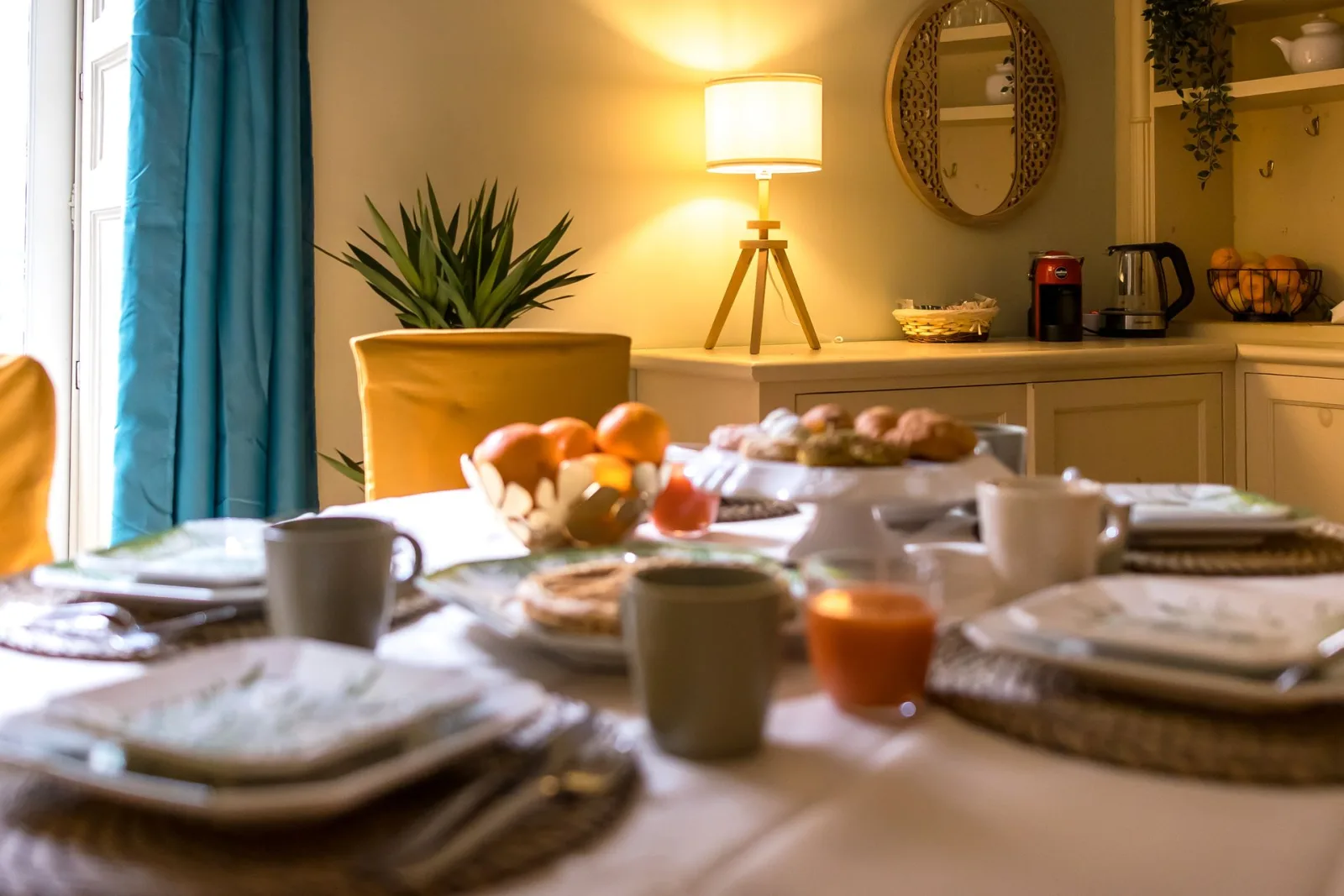 Breakfast table laid with fruit and pastries by the window