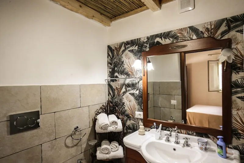 Bathroom with wooden vanity and leaf wallpaper