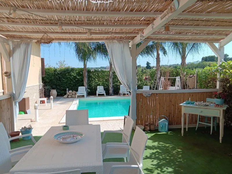 Pergola dining area on the lawn beside the pool