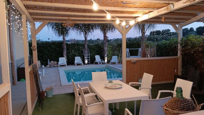 Pergola with string lights by the pool at dusk